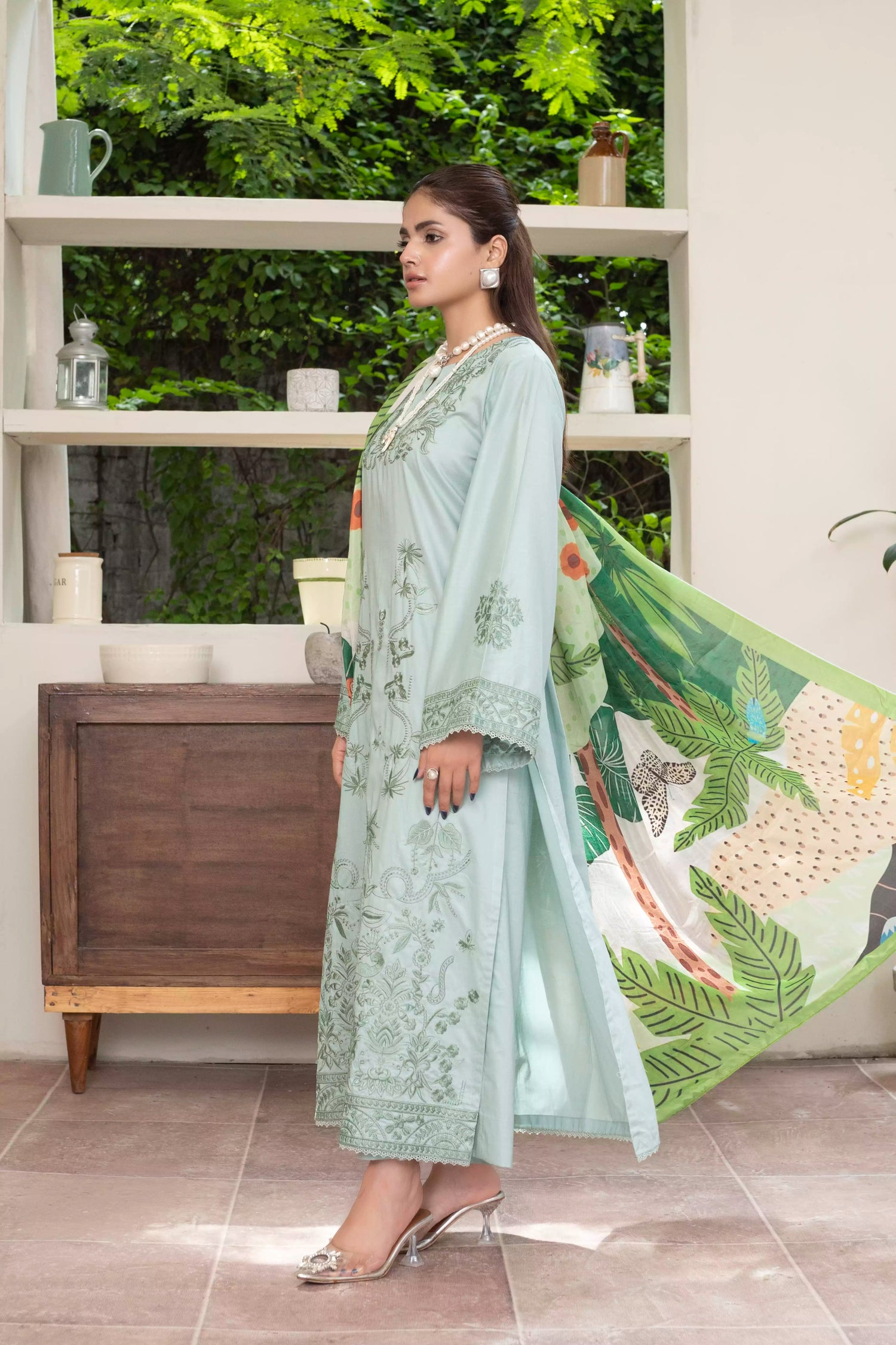 A pastel mint green design with embroidery on sleeves and intricate floral patterns, paired with a vibrant, tropical-themed printed dupatta.