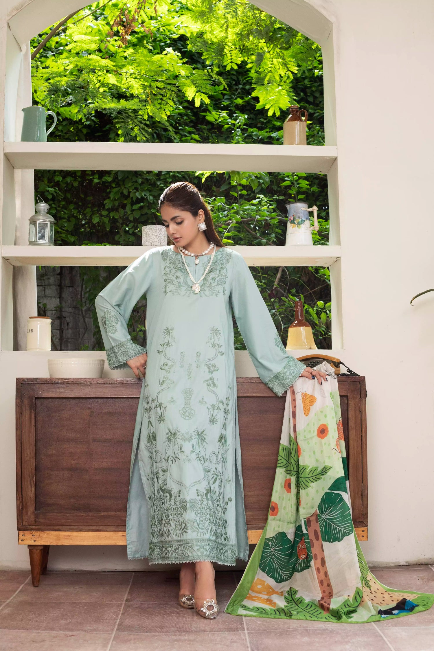 A pastel mint green design with embroidery on sleeves and intricate floral patterns, paired with a vibrant, tropical-themed printed dupatta.