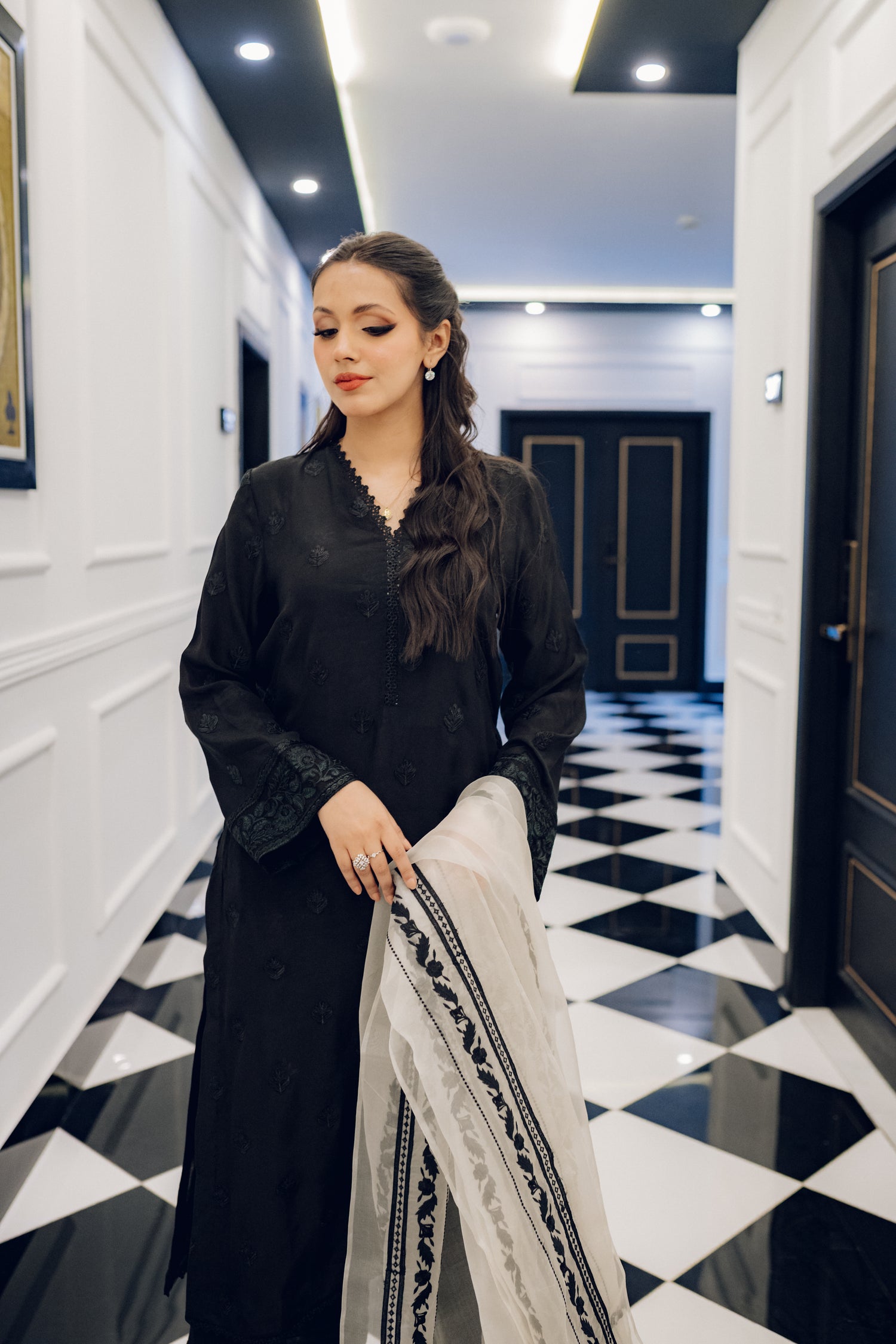 A black embroidered dress featuring celestial-inspired motifs and intricate lace detailing on the sleeves and pants, paired with a white organza dupatta adorned with coordinated embroidery for a refined, elegant contrast.