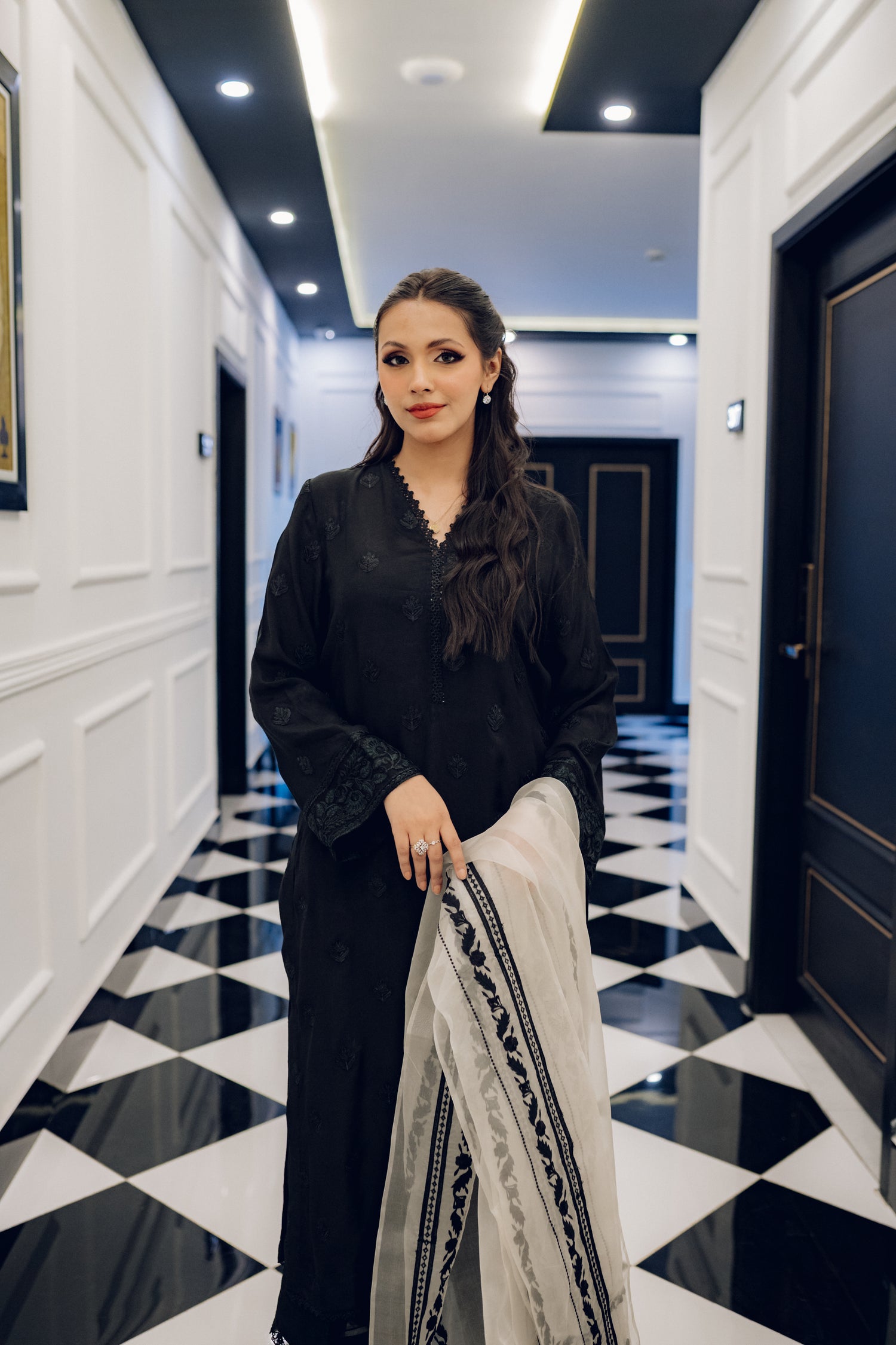 A black embroidered dress featuring celestial-inspired motifs and intricate lace detailing on the sleeves and pants, paired with a white organza dupatta adorned with coordinated embroidery for a refined, elegant contrast.