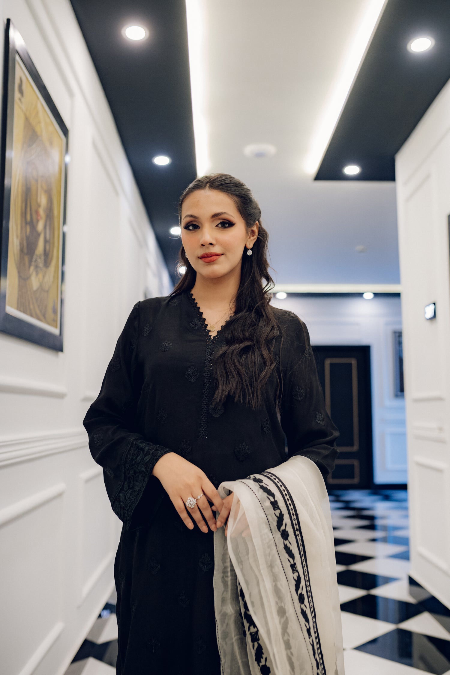 A black embroidered dress featuring celestial-inspired motifs and intricate lace detailing on the sleeves and pants, paired with a white organza dupatta adorned with coordinated embroidery for a refined, elegant contrast.