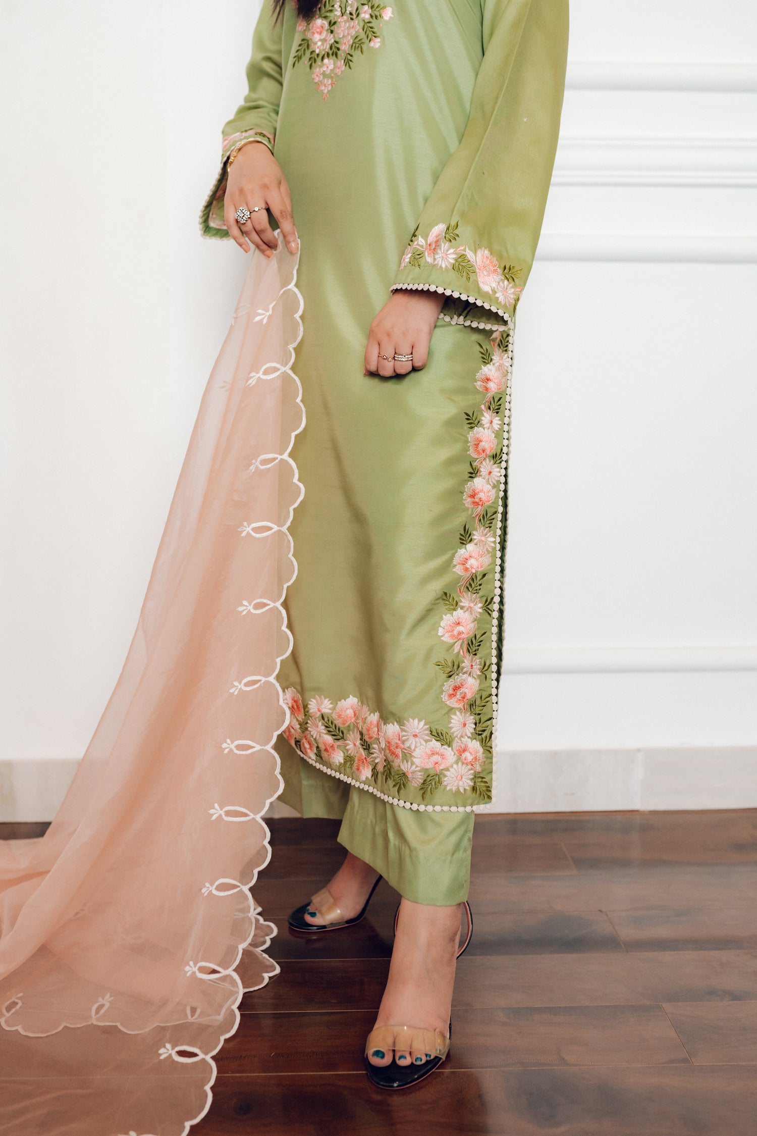 Vibrant leaf green colored dress with floral embroidery, paired with a peach pink cutwork dupatta, capturing the essence of spring with nature-inspired elegance and graceful charm.