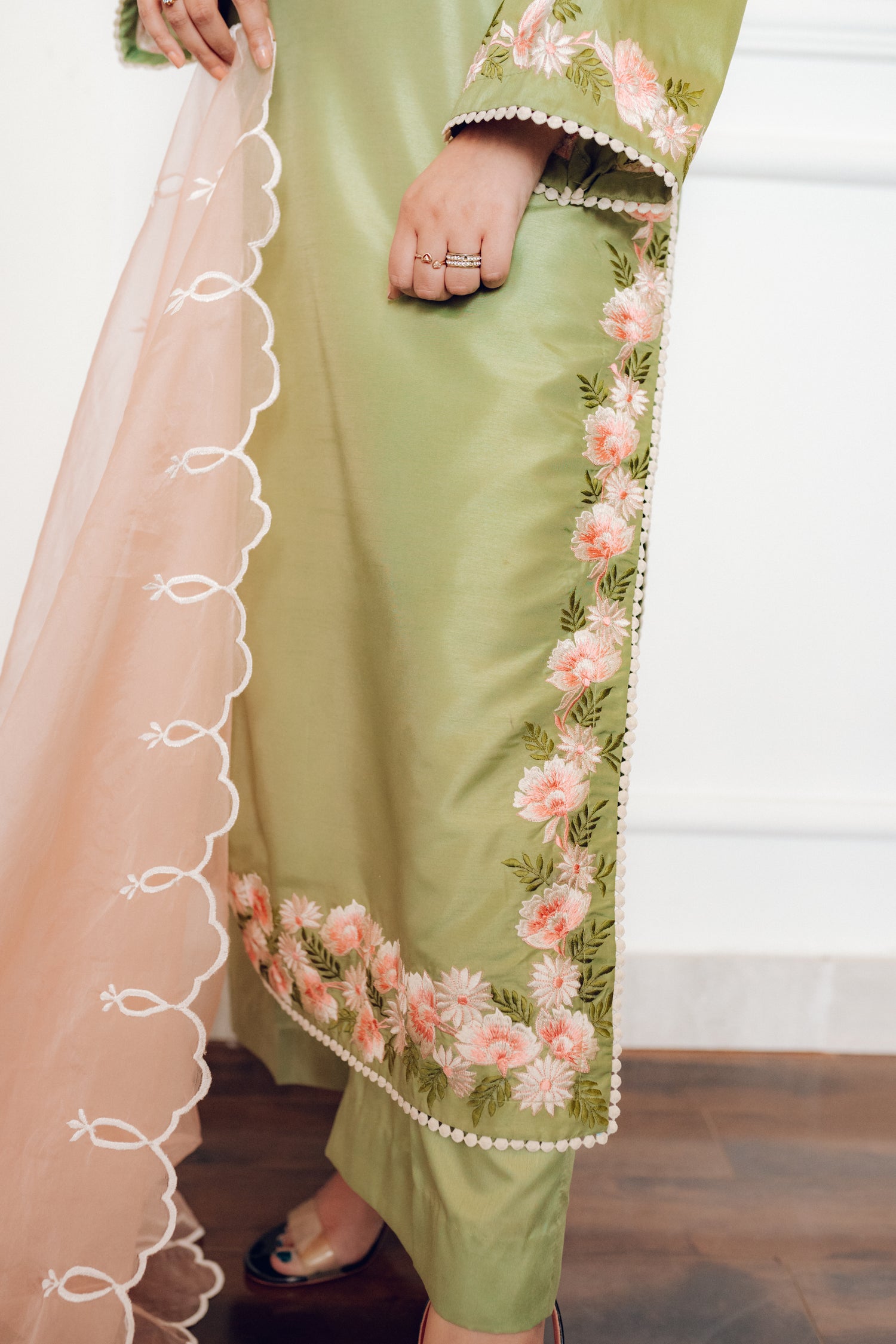 Vibrant leaf green colored dress with floral embroidery, paired with a peach pink cutwork dupatta, capturing the essence of spring with nature-inspired elegance and graceful charm.