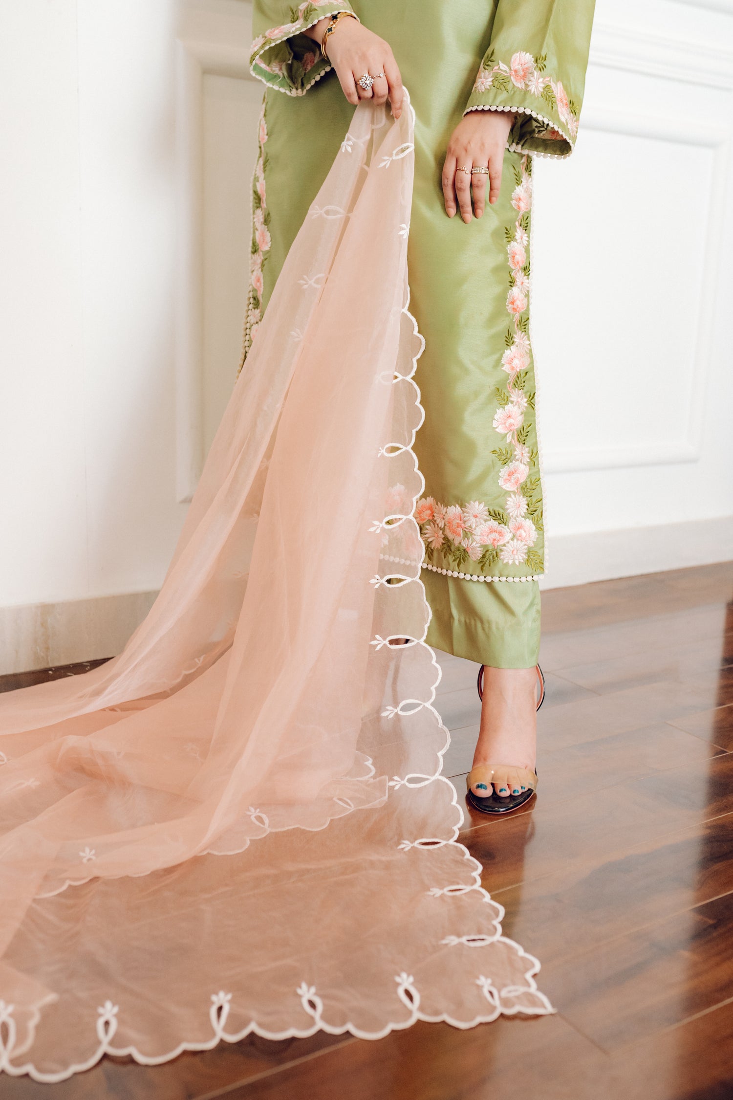 Vibrant leaf green colored dress with floral embroidery, paired with a peach pink cutwork dupatta, capturing the essence of spring with nature-inspired elegance and graceful charm.