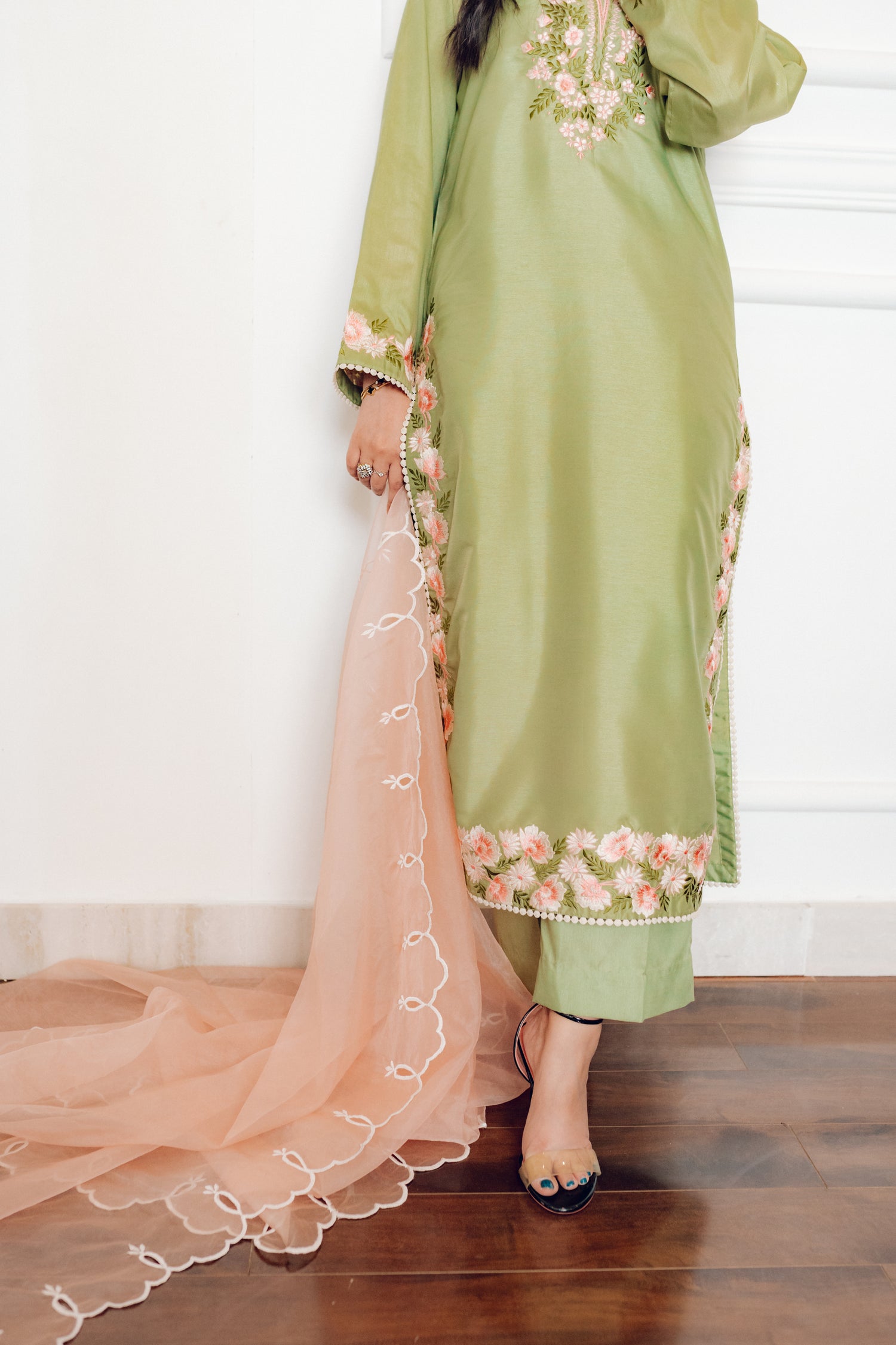 Vibrant leaf green colored dress with floral embroidery, paired with a peach pink cutwork dupatta, capturing the essence of spring with nature-inspired elegance and graceful charm.