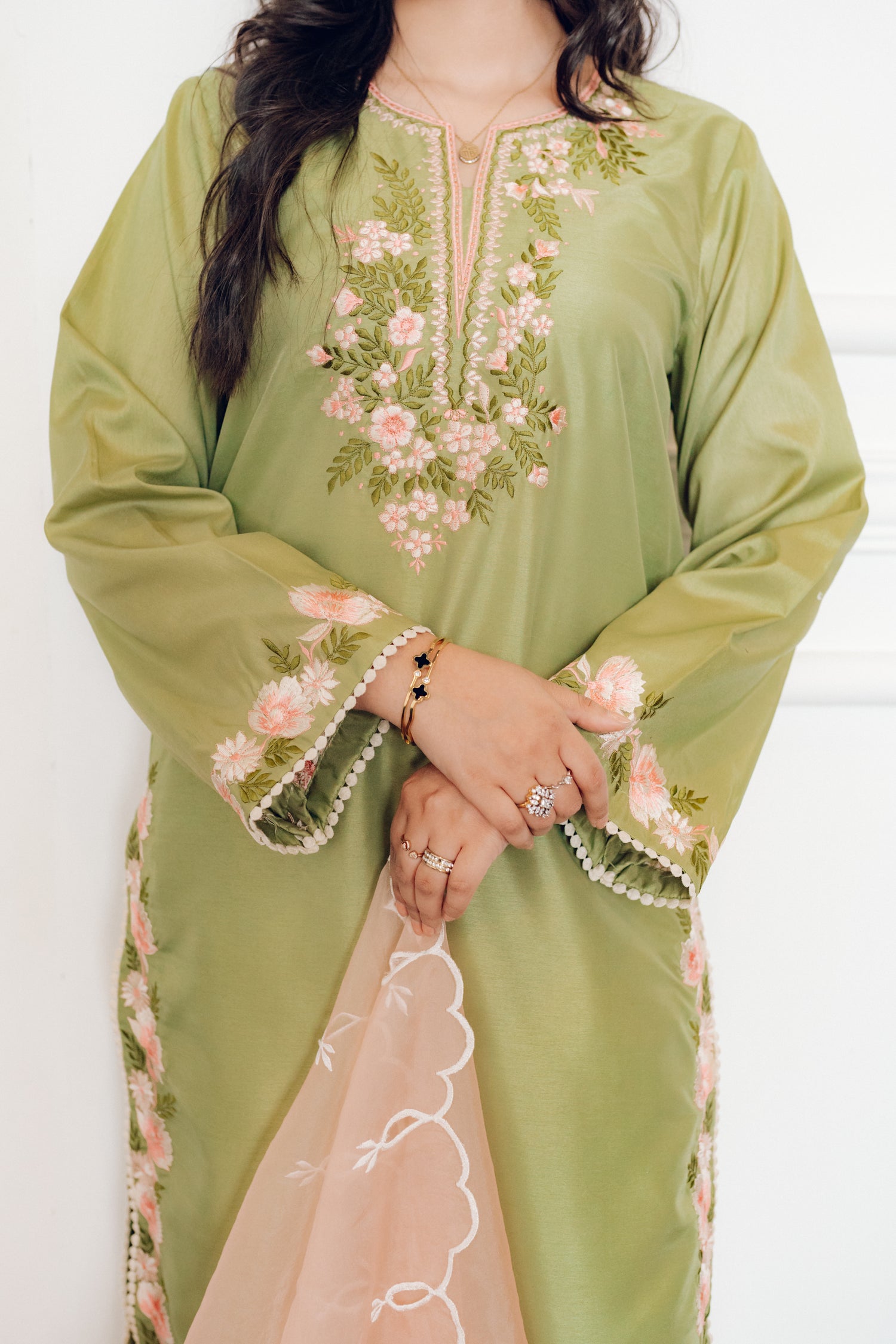 Vibrant leaf green colored dress with floral embroidery, paired with a peach pink cutwork dupatta, capturing the essence of spring with nature-inspired elegance and graceful charm.
