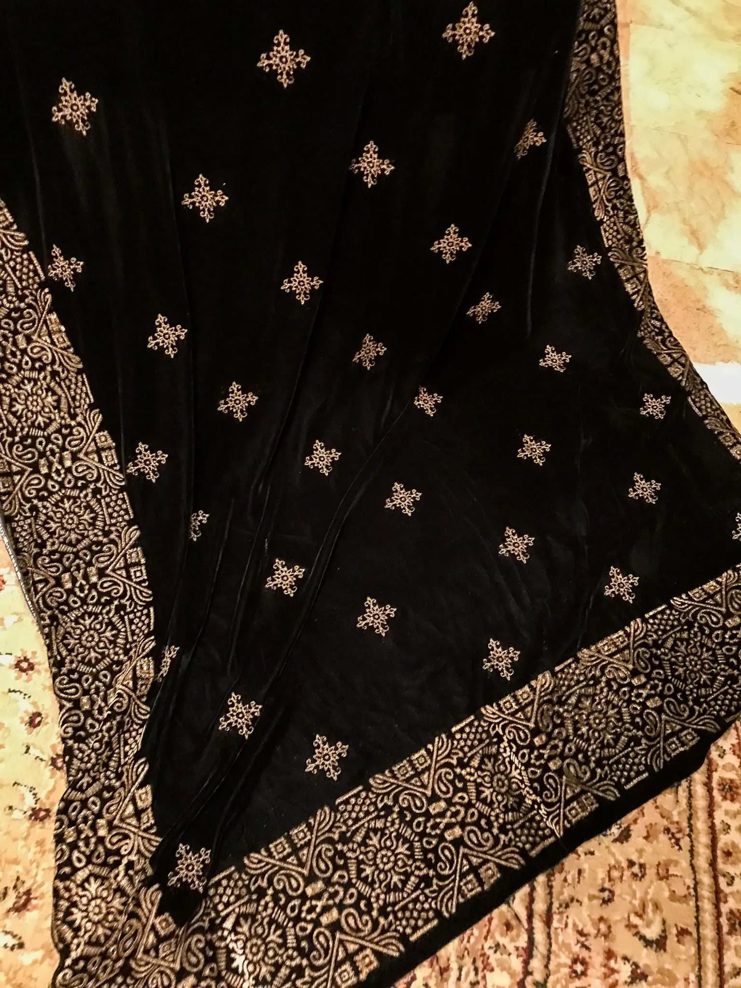 A Geometric Velvet Shawl showcasing intricate block printed motifs complimented with shimmering golden tila embroidery for stylish, glamourous look.