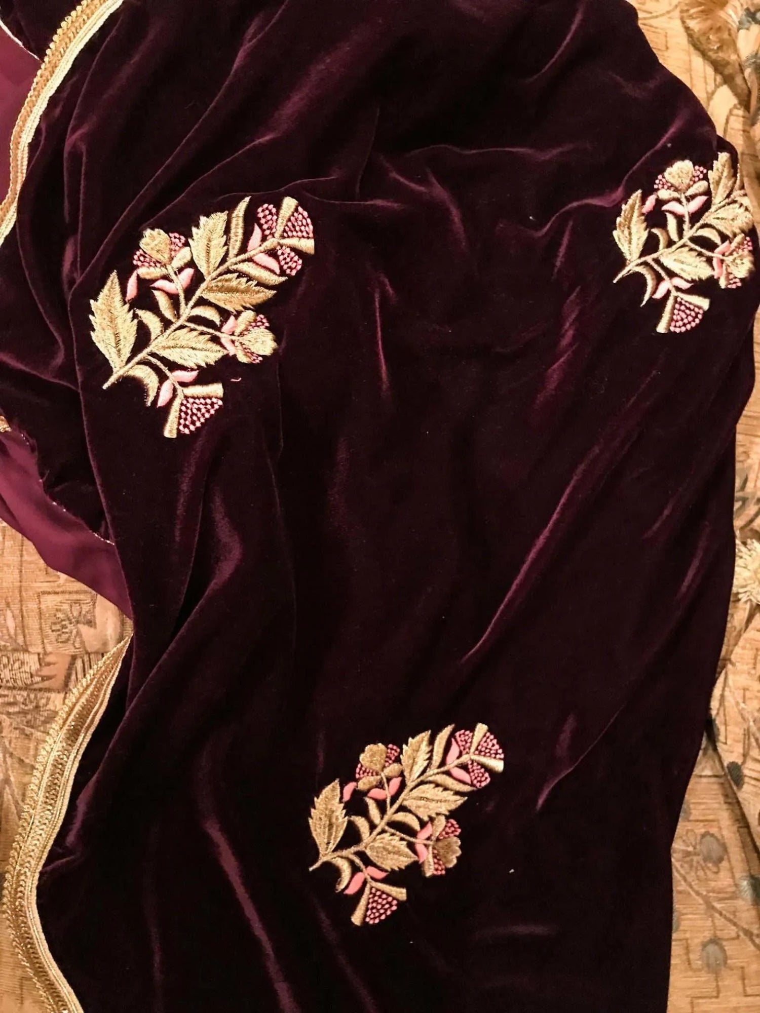 A luxurious velvet shawl featuring intricate gold embroidery and floral designs, exuding elegance, highlighting refined craftsmanship  and sophistication.