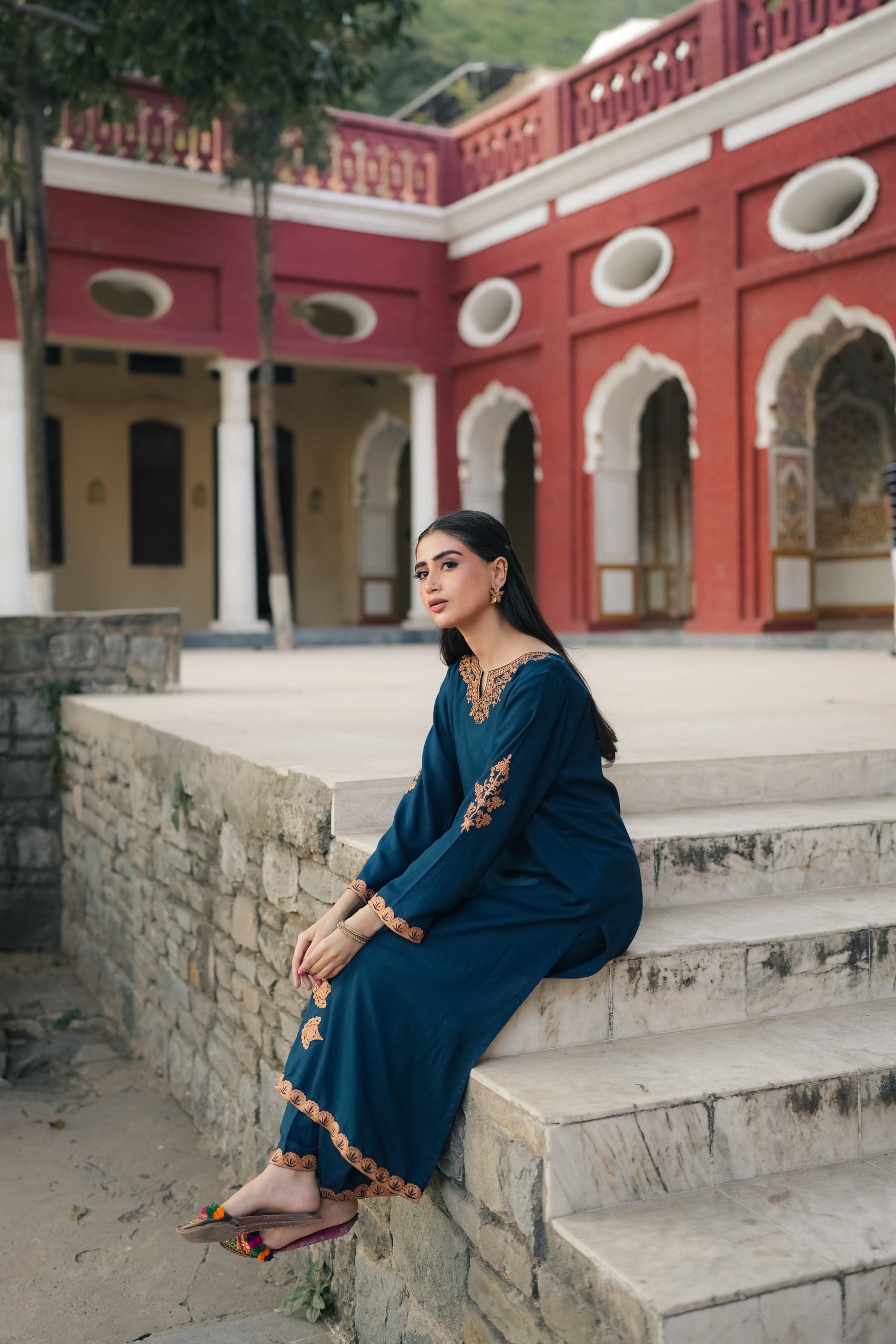 A Zinc blue ensemble featuring delicate light orange embroidery on the neckline, sleeves, and front with fine scattered motifs on the side. Soft threadwork paired with a matching shalwar. The outfit has an elegant, refined silhouette suitable for festive and everyday wear.