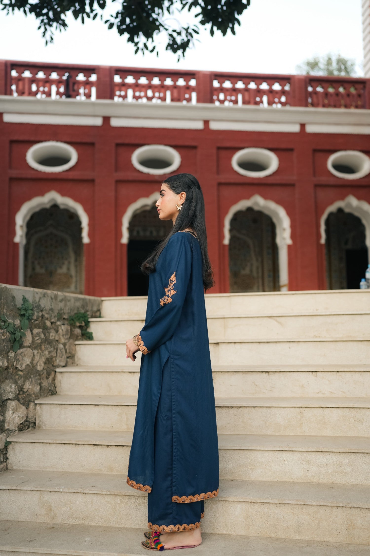 A Zinc blue ensemble featuring delicate light orange embroidery on the neckline, sleeves, and front with fine scattered motifs on the side. Soft threadwork paired with a matching shalwar. The outfit has an elegant, refined silhouette suitable for festive and everyday wear.